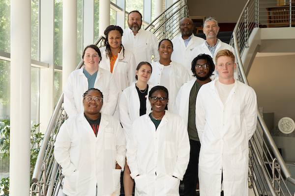 Seven students and four faculty standing in the Parkinson Hall stairwell.