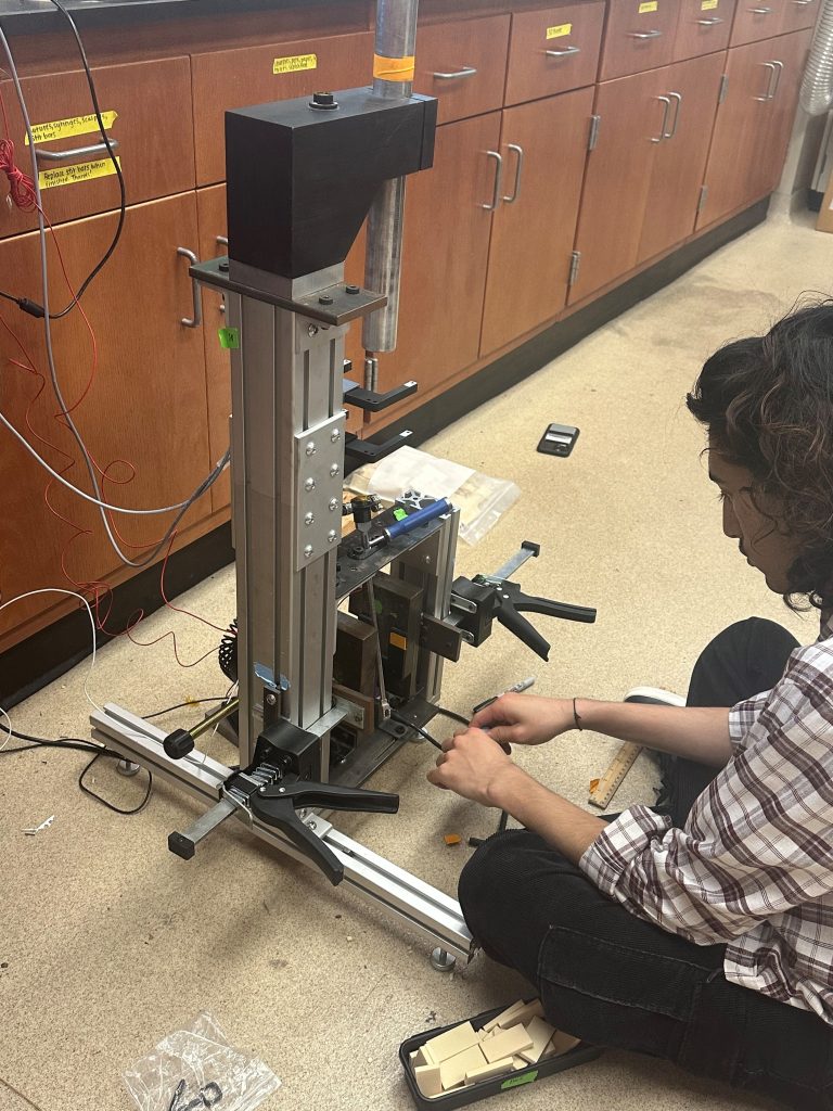 Student sitting on the floor with a mechanical device.