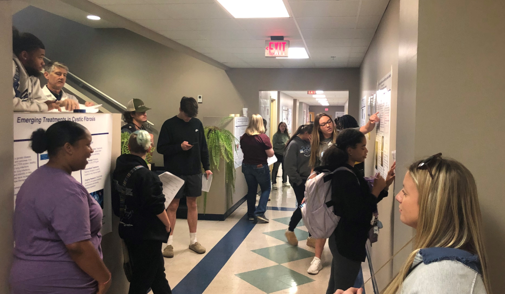 Student presenters and student attendees gather in Parkinson Hall hallway to view BS 400 posters.