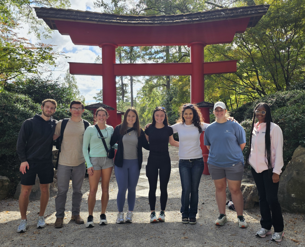 Eight students standing in front of a pagoda.